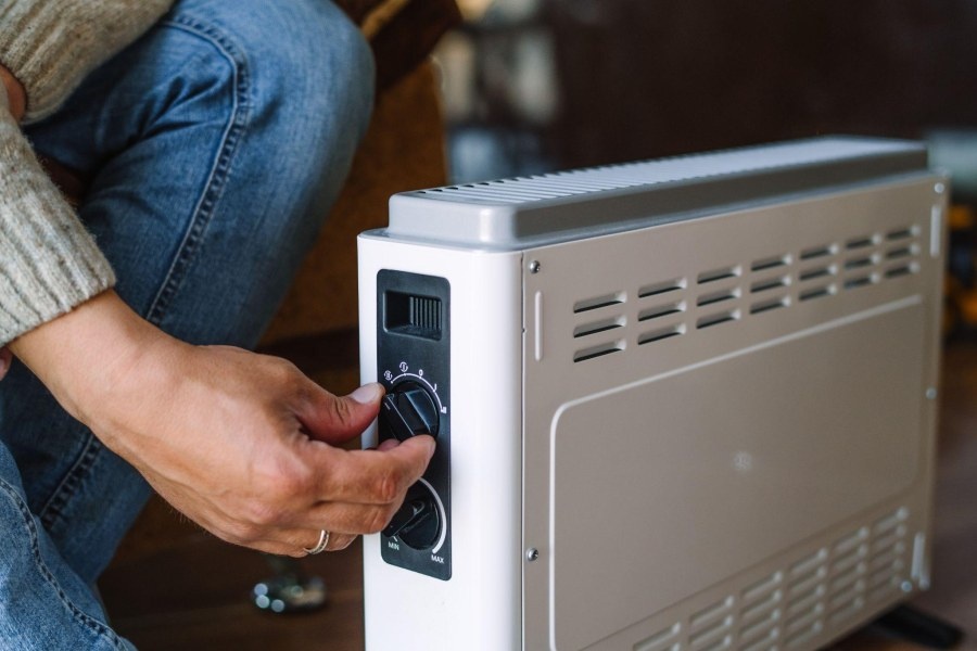 grzejnik elektryczny i dłoń na pokrętle