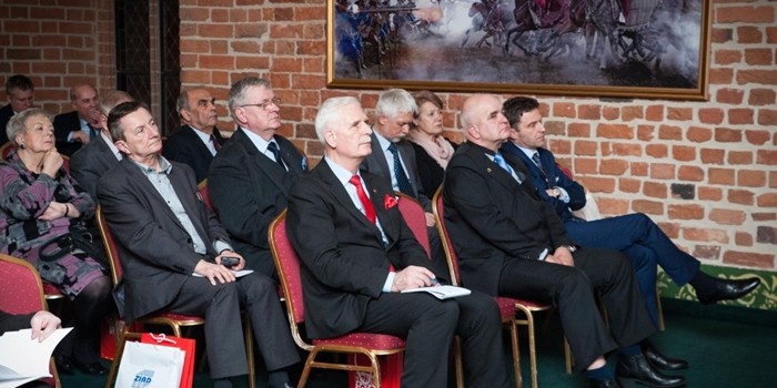 kilkanaście osób siedzi na krzesłach i słucha wystąpienia